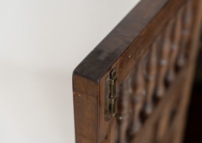 Stunning Spanish brutalist cabinet, 1950s. Striking and architectural, this 1950s Spanish cabinet is a powerful example of brutalist craftsmanship. Executed in solid wood, it features a deeply carved geometric façade with repetitive panel motifs that create a strong sense of rhythm and depth. The upper doors are accented with turned spindle details, adding contrast to the otherwise bold and graphic design. Original iron hardware, including hinges and latches, reinforces its rustic character. Behind the doors, the cabinet offers generous storage, making it as functional as it is sculptural. The warm patina of the wood enhances its presence, giving it a timeless, almost monolithic feel.
