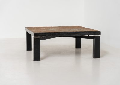 Brutalist Coffee Table in Norwegian Slate stone, 1970s A very powerful Brutalist coffee table from the 1970s, defined by its strong architectural presence and sculptural simplicity. The substantial tabletop is crafted from Norwegian slate, showcasing a rich and varied surface with natural tonal shifts that create depth and visual texture. The solid stone top is supported by a black lacquered metal base, offering a bold contrast while reinforcing the table’s grounded and monolithic character. The table remains in very good condition, with light, age-appropriate wear such as minor scratches to the frame.