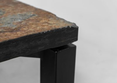 Brutalist Coffee Table in Norwegian Slate stone, 1970s A very powerful Brutalist coffee table from the 1970s, defined by its strong architectural presence and sculptural simplicity. The substantial tabletop is crafted from Norwegian slate, showcasing a rich and varied surface with natural tonal shifts that create depth and visual texture. The solid stone top is supported by a black lacquered metal base, offering a bold contrast while reinforcing the table’s grounded and monolithic character. The table remains in very good condition, with light, age-appropriate wear such as minor scratches to the frame.