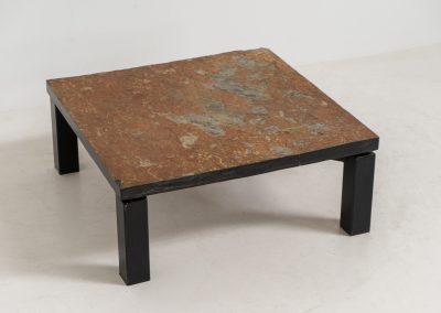 Brutalist Coffee Table in Norwegian Slate stone, 1970s A very powerful Brutalist coffee table from the 1970s, defined by its strong architectural presence and sculptural simplicity. The substantial tabletop is crafted from Norwegian slate, showcasing a rich and varied surface with natural tonal shifts that create depth and visual texture. The solid stone top is supported by a black lacquered metal base, offering a bold contrast while reinforcing the table’s grounded and monolithic character. The table remains in very good condition, with light, age-appropriate wear such as minor scratches to the frame.