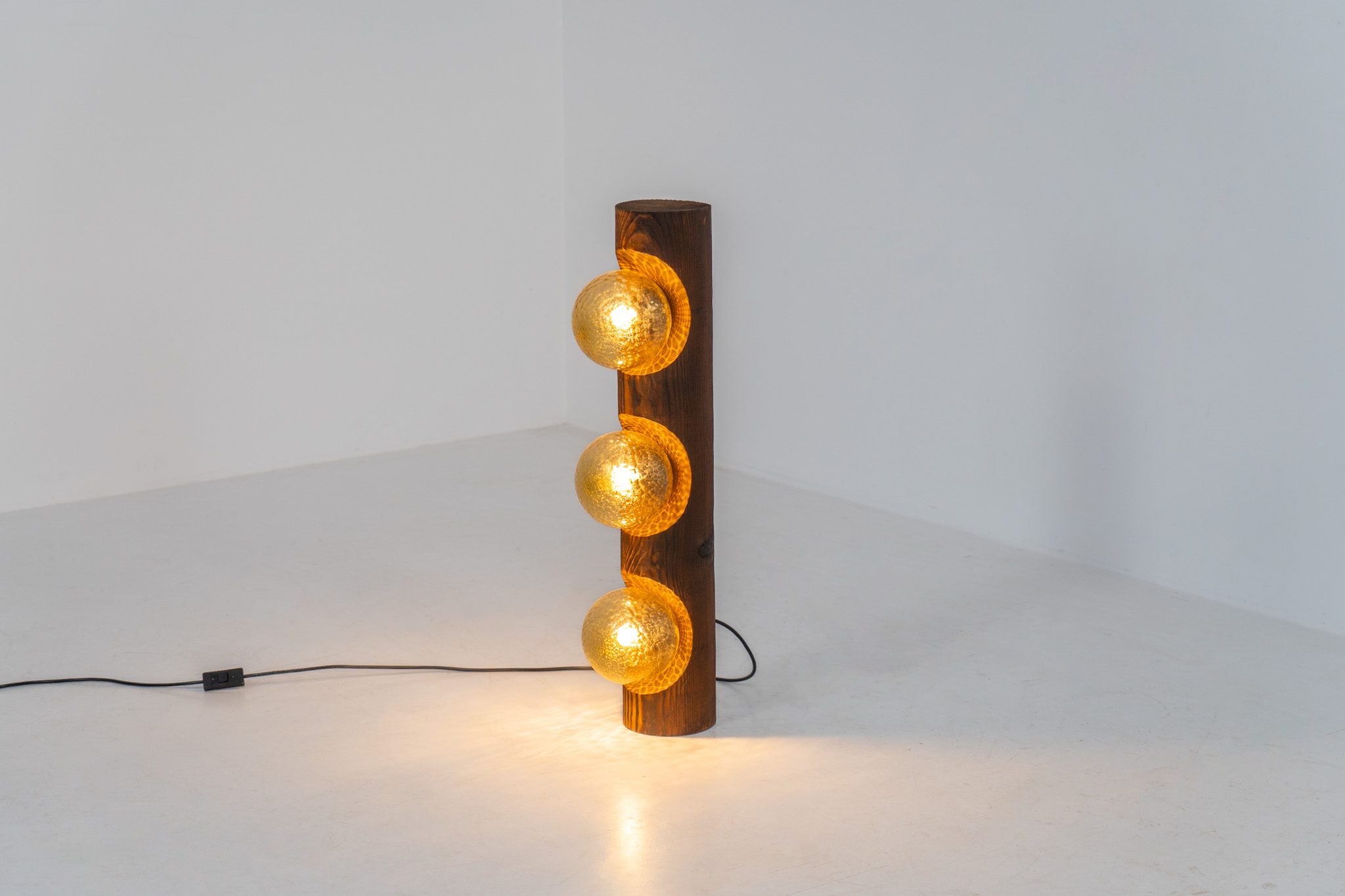 Sculptural floor lamp by Temde Leuchten (Switzerland, 1970s). This exceptional piece combines an organic form with a subtle brutalist character. It is crafted from solid burnt oak and features three round glass light sources that create a warm, atmospheric glow. Versatile in use, the lamp can function as a mid-height floor lamp, a table lamp, or even a wall-mounted piece thanks to its integrated rear mountings. The lamp remains in very good condition, with the wood showing a beautifully aged patina that enhances its character.
