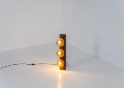 Sculptural floor lamp by Temde Leuchten (Switzerland, 1970s). This exceptional piece combines an organic form with a subtle brutalist character. It is crafted from solid burnt oak and features three round glass light sources that create a warm, atmospheric glow. Versatile in use, the lamp can function as a mid-height floor lamp, a table lamp, or even a wall-mounted piece thanks to its integrated rear mountings. The lamp remains in very good condition, with the wood showing a beautifully aged patina that enhances its character.