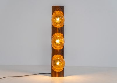 Sculptural floor lamp by Temde Leuchten (Switzerland, 1970s). This exceptional piece combines an organic form with a subtle brutalist character. It is crafted from solid burnt oak and features three round glass light sources that create a warm, atmospheric glow. Versatile in use, the lamp can function as a mid-height floor lamp, a table lamp, or even a wall-mounted piece thanks to its integrated rear mountings. The lamp remains in very good condition, with the wood showing a beautifully aged patina that enhances its character.