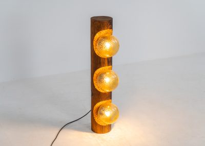 Sculptural floor lamp by Temde Leuchten (Switzerland, 1970s). This exceptional piece combines an organic form with a subtle brutalist character. It is crafted from solid burnt oak and features three round glass light sources that create a warm, atmospheric glow. Versatile in use, the lamp can function as a mid-height floor lamp, a table lamp, or even a wall-mounted piece thanks to its integrated rear mountings. The lamp remains in very good condition, with the wood showing a beautifully aged patina that enhances its character.