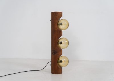 Sculptural floor lamp by Temde Leuchten (Switzerland, 1970s). This exceptional piece combines an organic form with a subtle brutalist character. It is crafted from solid burnt oak and features three round glass light sources that create a warm, atmospheric glow. Versatile in use, the lamp can function as a mid-height floor lamp, a table lamp, or even a wall-mounted piece thanks to its integrated rear mountings. The lamp remains in very good condition, with the wood showing a beautifully aged patina that enhances its character.