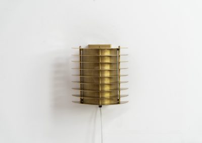 Wall light by Borens (Sweden, 1980s). A refined example of Scandinavian modernism, this wall lamp features layered metal shades surrounding a perforated inner cylinder, creating a warm, diffused glow. The structured, almost architectural design adds depth while maintaining a clean and balanced aesthetic. In very good vintage condition with a mild patina to the metal. Marked by maker.