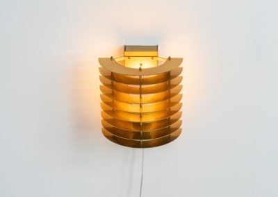 Wall light by Borens (Sweden, 1980s). A refined example of Scandinavian modernism, this wall lamp features layered metal shades surrounding a perforated inner cylinder, creating a warm, diffused glow. The structured, almost architectural design adds depth while maintaining a clean and balanced aesthetic. In very good vintage condition with a mild patina to the metal. Marked by maker.