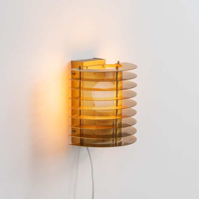 Wall light by Borens (Sweden, 1980s). A refined example of Scandinavian modernism, this wall lamp features layered metal shades surrounding a perforated inner cylinder, creating a warm, diffused glow. The structured, almost architectural design adds depth while maintaining a clean and balanced aesthetic. In very good vintage condition with a mild patina to the metal. Marked by maker.