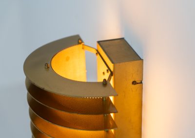 Wall light by Borens (Sweden, 1980s). A refined example of Scandinavian modernism, this wall lamp features layered metal shades surrounding a perforated inner cylinder, creating a warm, diffused glow. The structured, almost architectural design adds depth while maintaining a clean and balanced aesthetic. In very good vintage condition with a mild patina to the metal. Marked by maker.