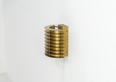 Wall light by Borens (Sweden, 1980s). A refined example of Scandinavian modernism, this wall lamp features layered metal shades surrounding a perforated inner cylinder, creating a warm, diffused glow. The structured, almost architectural design adds depth while maintaining a clean and balanced aesthetic. In very good vintage condition with a mild patina to the metal. Marked by maker.