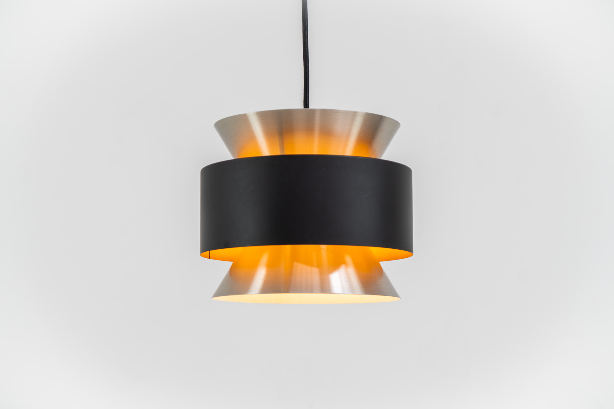 Stunning pendant light by Carl Thore for Granhaga (Sweden, 1960s). A sleek design featuring two aluminium shades and a black halo which is lacquered in yellow on the inside. The yellow interior creates a beautiful defused and moody light dispersion. The lamp remains in very good condition.