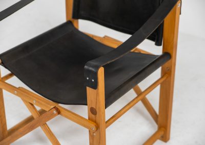 Oak & leather safari chair (Denmark, 1980s) A striking armchair from the 1980s, crafted from solid oak and fitted with a black leather seat and backrest. The design features a sturdy, architectural frame with visible joinery and cross-bracing, giving it a strong yet refined presence. It is easily foldable, reducing its footprint by roughly half when stored. The chair is in good condition, showing light signs of use and a beautiful natural patina on the leather.