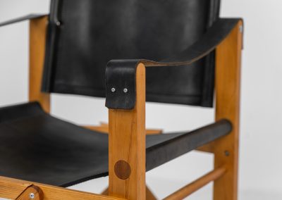 Oak & leather safari chair (Denmark, 1980s) A striking armchair from the 1980s, crafted from solid oak and fitted with a black leather seat and backrest. The design features a sturdy, architectural frame with visible joinery and cross-bracing, giving it a strong yet refined presence. It is easily foldable, reducing its footprint by roughly half when stored. The chair is in good condition, showing light signs of use and a beautiful natural patina on the leather.