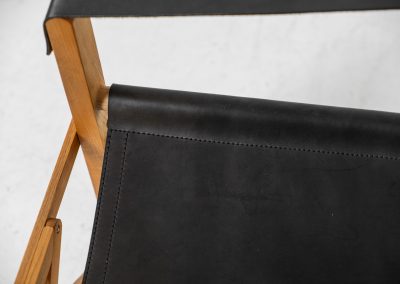 Oak & leather safari chair (Denmark, 1980s) A striking armchair from the 1980s, crafted from solid oak and fitted with a black leather seat and backrest. The design features a sturdy, architectural frame with visible joinery and cross-bracing, giving it a strong yet refined presence. It is easily foldable, reducing its footprint by roughly half when stored. The chair is in good condition, showing light signs of use and a beautiful natural patina on the leather.