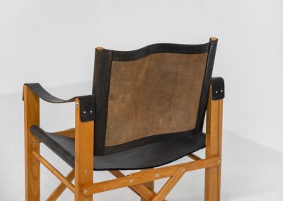 Oak & leather safari chair (Denmark, 1980s) A striking armchair from the 1980s, crafted from solid oak and fitted with a black leather seat and backrest. The design features a sturdy, architectural frame with visible joinery and cross-bracing, giving it a strong yet refined presence. It is easily foldable, reducing its footprint by roughly half when stored. The chair is in good condition, showing light signs of use and a beautiful natural patina on the leather.
