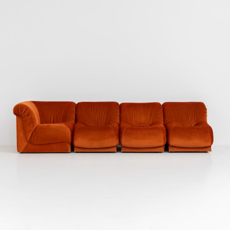Modular sofa by Doimo Salotti (Italy, 1970s). Striking and bold modular seating system consisting of three identical elements and one corner piece, upholstered in their original vivid orange velvet. Can be arranged as a sofa or used as individual lounge chairs. Low, sculptural design with generous padding, offering both strong visual impact and excellent comfort. Professionally deep-cleaned and in very good original condition, with minor age-related wear. Some cracks to the underside dust covers (purely cosmetic, no impact on use or structure). Marked by maker.