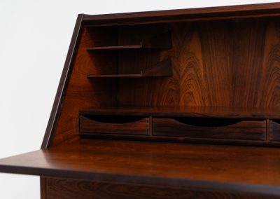 “No. 63” secretary by Kai Kristiansen for Torring Møbelfabrik (Denmark, 1960s). This very hard to find piece is one of our favorite secretaries and an example of high quality Danish craftsmanship. It features stunning aesthetics and nifty details like the sculptural handles or the convenient pivoting drop-down leaf. This particular piece is crafted out of rosewood and has an extraordinary woodgrain! It is in splendid condition with a minor repair mark on the lowest drawer.