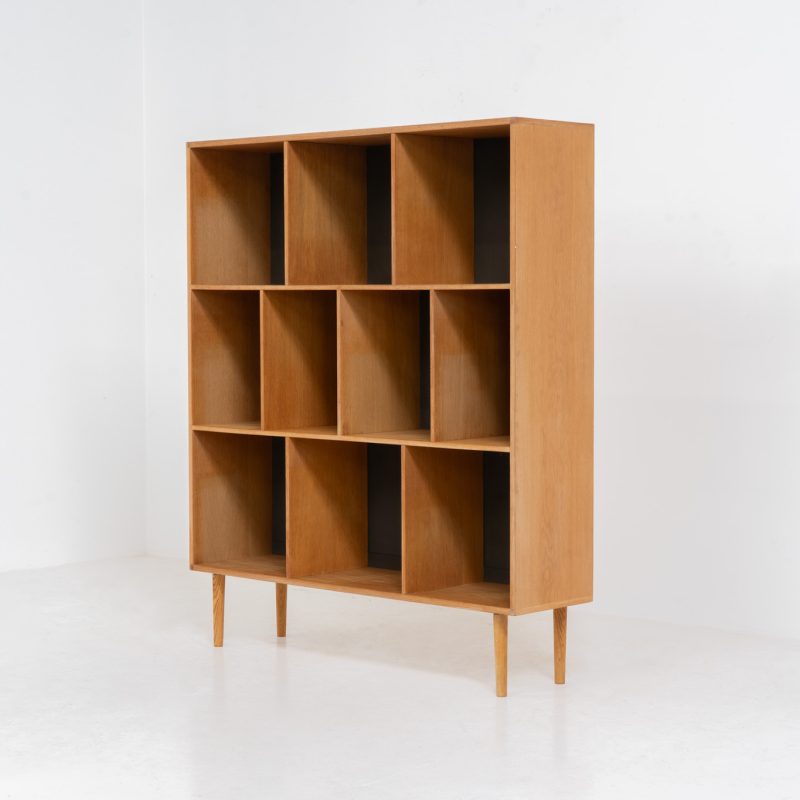 Oak bookcase by Kurt Østervig (Denmark, 1960s). A minimalistic bookcase crated in oak with vertical adjustable shelves and a contrasting dark back plate. In good condition with some discoloration on the inside.