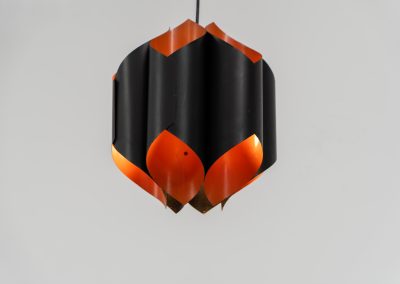 Sculptural pendant light by Bent Karlby for Lyfa (Denmark, 1960s). A bold, architectural design with folded metal shades in black and orange, creating a striking contrast and a warm, indirect glow. The layered construction plays with light and shadow, giving the piece a dynamic, almost graphic presence. A true mid-century statement. Compact, sculptural, and highly distinctive. Perfect as a focal point in any interior. In very good condition with age related wear.