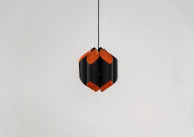Sculptural pendant light by Bent Karlby for Lyfa (Denmark, 1960s). A bold, architectural design with folded metal shades in black and orange, creating a striking contrast and a warm, indirect glow. The layered construction plays with light and shadow, giving the piece a dynamic, almost graphic presence. A true mid-century statement. Compact, sculptural, and highly distinctive. Perfect as a focal point in any interior. In very good condition with age related wear.
