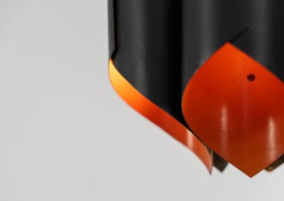 Sculptural pendant light by Bent Karlby for Lyfa (Denmark, 1960s). A bold, architectural design with folded metal shades in black and orange, creating a striking contrast and a warm, indirect glow. The layered construction plays with light and shadow, giving the piece a dynamic, almost graphic presence. A true mid-century statement. Compact, sculptural, and highly distinctive. Perfect as a focal point in any interior. In very good condition with age related wear.