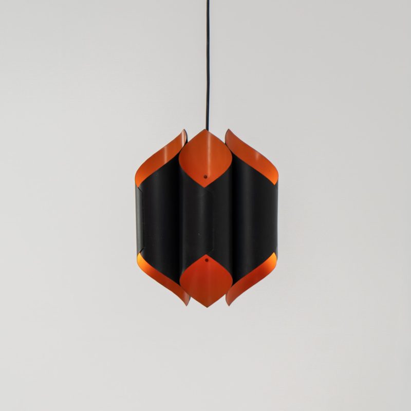 Sculptural pendant light by Bent Karlby for Lyfa (Denmark, 1960s). A bold, architectural design with folded metal shades in black and orange, creating a striking contrast and a warm, indirect glow. The layered construction plays with light and shadow, giving the piece a dynamic, almost graphic presence. A true mid-century statement. Compact, sculptural, and highly distinctive. Perfect as a focal point in any interior. In very good condition with age related wear.