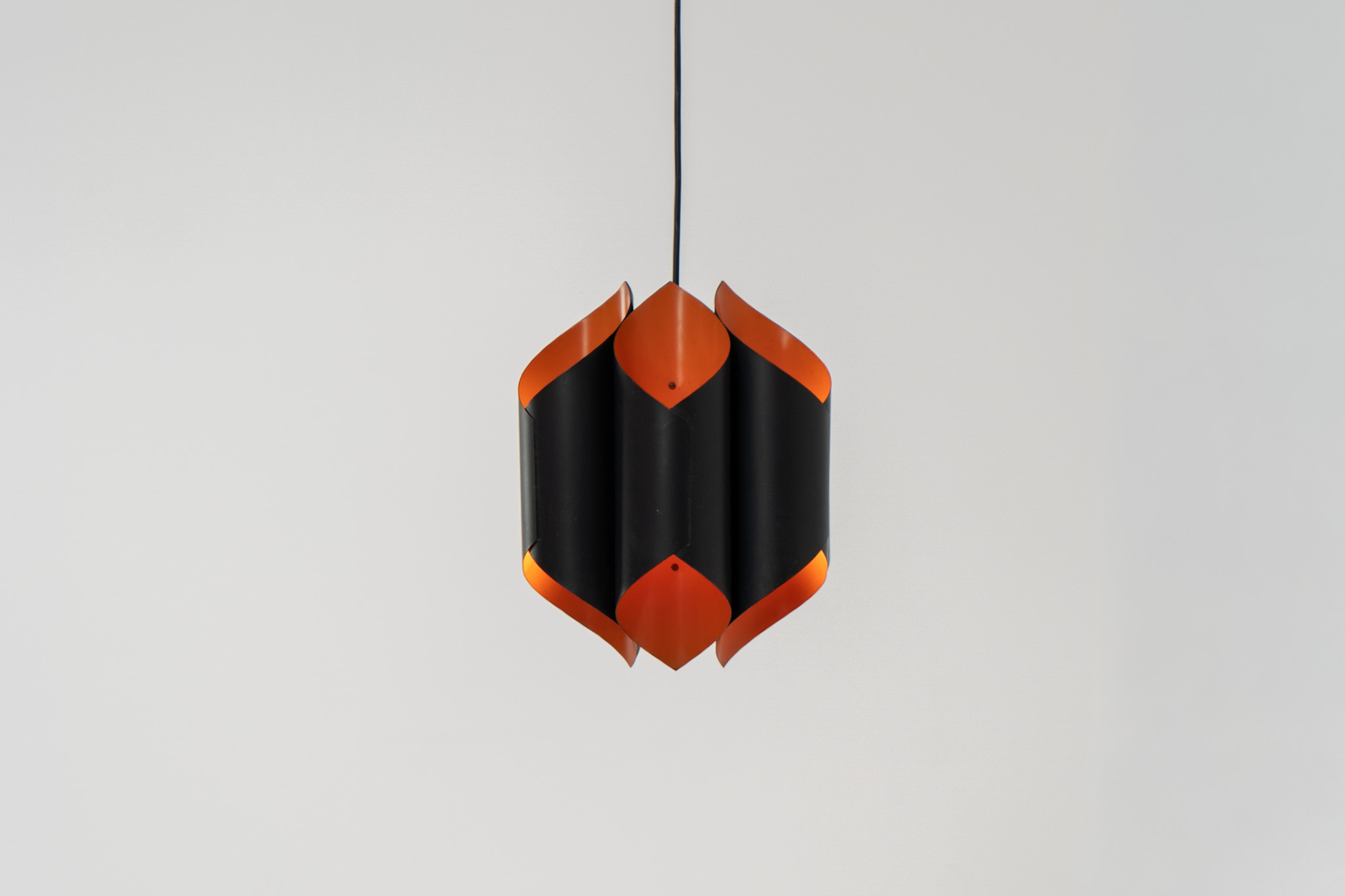 Sculptural pendant light by Bent Karlby for Lyfa (Denmark, 1960s). A bold, architectural design with folded metal shades in black and orange, creating a striking contrast and a warm, indirect glow. The layered construction plays with light and shadow, giving the piece a dynamic, almost graphic presence. A true mid-century statement. Compact, sculptural, and highly distinctive. Perfect as a focal point in any interior. In very good condition with age related wear.