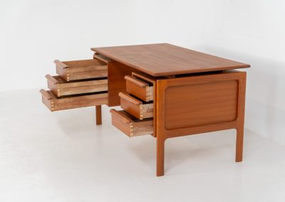 Teak writing desk by Arne Vodder for G.V. Møbler (Denmark, 1960s). This exceptionally beautiful piece is a true example of top-quality Danish craftsmanship. Made from teak, it showcases elegant aesthetics with softly rounded edges and a floating desk top. It contains six very deep drawers and a finished backside, making it an ideal piece for placement in the center of a room. The desk is in excellent condition.