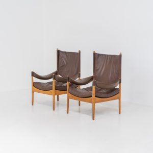 Pair of “Modus” armchairs by Kristian Vedel for Søren Willadsen (Denmark, 1960s). A rare and authentic set of two lounge chairs crafted from solid oak with beautifully detailed joinery. The frames have been carefully refreshed while preserving the wood's original character and warm patina. The brown leather has been cleaned and conditioned, showing attractive age and wear consistent with its vintage nature. A great example of Danish mid-century design, combining elegant sculptural lines with exceptional comfort thanks to the wide seats, suspended leather backs, and generous cushions.