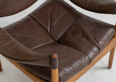 Pair of “Modus” armchairs by Kristian Vedel for Søren Willadsen (Denmark, 1960s). A rare and authentic set of two lounge chairs crafted from solid oak with beautifully detailed joinery. The frames have been carefully refreshed while preserving the wood's original character and warm patina. The brown leather has been cleaned and conditioned, showing attractive age and wear consistent with its vintage nature. A great example of Danish mid-century design, combining elegant sculptural lines with exceptional comfort thanks to the wide seats, suspended leather backs, and generous cushions.