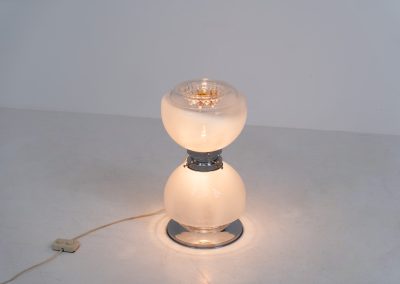 Floor lamp by Toni Zuccheri for Mazzega (Italy, 1970s). 1970s floor lamp by Toni Zuccheri for Mazzega, combining sculptural opaline Murano glass with refined chrome details. The design is highlighted by subtle amber, drip-like inclusions, an iconic Zuccheri signature. When lit, it casts a warm, atmospheric glow that enhances the soft translucency of the glass, making it both a functional light source and a collectible piece of Italian design. The lamp can be used as a floor lamp, or a large table lamp. Splendid condition.