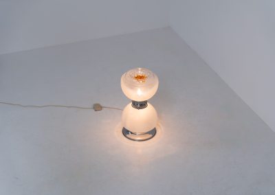 Floor lamp by Toni Zuccheri for Mazzega (Italy, 1970s). 1970s floor lamp by Toni Zuccheri for Mazzega, combining sculptural opaline Murano glass with refined chrome details. The design is highlighted by subtle amber, drip-like inclusions, an iconic Zuccheri signature. When lit, it casts a warm, atmospheric glow that enhances the soft translucency of the glass, making it both a functional light source and a collectible piece of Italian design. The lamp can be used as a floor lamp, or a large table lamp. Splendid condition.