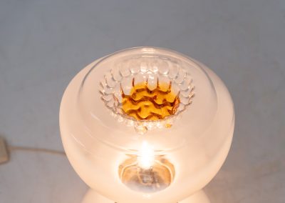 Floor lamp by Toni Zuccheri for Mazzega (Italy, 1970s). 1970s floor lamp by Toni Zuccheri for Mazzega, combining sculptural opaline Murano glass with refined chrome details. The design is highlighted by subtle amber, drip-like inclusions, an iconic Zuccheri signature. When lit, it casts a warm, atmospheric glow that enhances the soft translucency of the glass, making it both a functional light source and a collectible piece of Italian design. The lamp can be used as a floor lamp, or a large table lamp. Splendid condition.