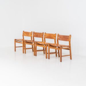 Oak & leather dining chairs (Denmark, 1960s). This exceptional set of dining chairs features solid oak frames paired with saddle leather seats. The design is reminiscent of Børge Mogensen’s “Spanish” dining chairs and could possibly be an lesser-known design by Mogensen, although this cannot be confirmed. The leather is in well-used condition with a beautiful, authentic patina. It shows some surface cracking, but this is limited to the top layer only and does not affect the structural integrity or strength of the seats.