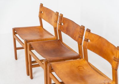 Oak & leather dining chairs (Denmark, 1960s). This exceptional set of dining chairs features solid oak frames paired with saddle leather seats. The design is reminiscent of Børge Mogensen’s “Spanish” dining chairs and could possibly be an lesser-known design by Mogensen, although this cannot be confirmed. The leather is in well-used condition with a beautiful, authentic patina. It shows some surface cracking, but this is limited to the top layer only and does not affect the structural integrity or strength of the seats.