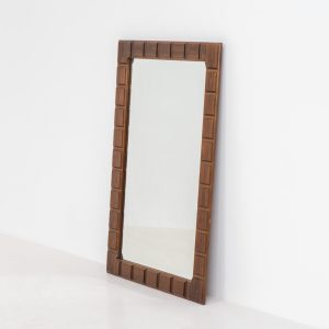 Sculptural graphic wall mirror (Sweden, 1960s). This wall mirror is made out of stained oak and offers a deeply carved geometric facade which creates a strong sense of rhythm and depth. The mirror is in very good condition.