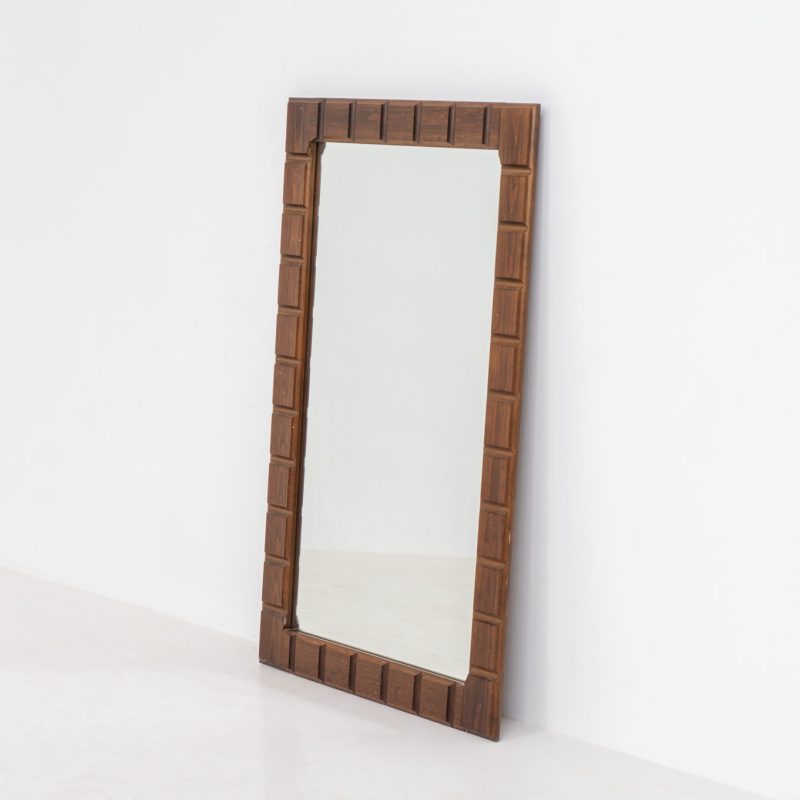 Sculptural graphic wall mirror (Sweden, 1960s). This wall mirror is made out of stained oak and offers a deeply carved geometric facade which creates a strong sense of rhythm and depth. The mirror is in very good condition.