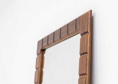 Sculptural graphic wall mirror (Sweden, 1960s). This wall mirror is made out of stained oak and offers a deeply carved geometric facade which creates a strong sense of rhythm and depth. The mirror is in very good condition.