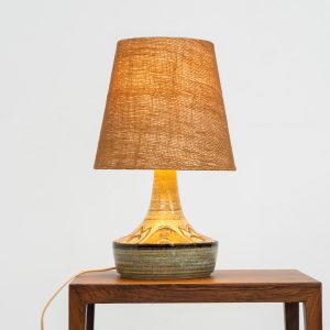Ceramic table lamp by Søholm for Bornholmsk (Denmark, 1960s). This lamp offers a refined blend of beautiful textures and timeless design. It has handcrafted ceramic base with earthy colors, complimented by a raffia shade. The lamp is marked and remains in splendid condition.