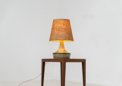 Ceramic table lamp by Søholm for Bornholmsk (Denmark, 1960s). This lamp offers a refined blend of beautiful textures and timeless design. It has handcrafted ceramic base with earthy colors, complimented by a raffia shade. The lamp is marked and remains in splendid condition.