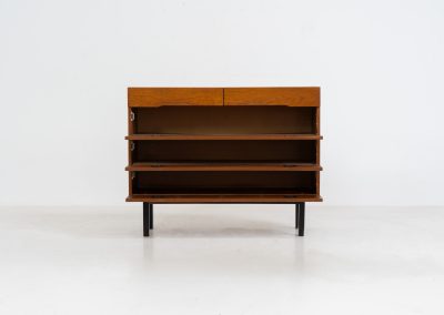 Teak shoe cabinet (Germany, 1960s). The cabinet features two small drawers and three shelves for shoe storage. It is made of teak and has a black lacquered frame with black inset handles that allow for proper ventilation. The cabinet is in good condition, with some visible signs of use.