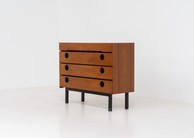 Teak shoe cabinet (Germany, 1960s). The cabinet features two small drawers and three shelves for shoe storage. It is made of teak and has a black lacquered frame with black inset handles that allow for proper ventilation. The cabinet is in good condition, with some visible signs of use.