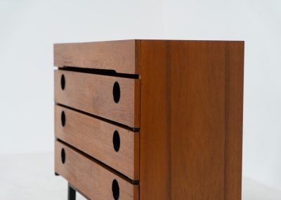Teak shoe cabinet (Germany, 1960s). The cabinet features two small drawers and three shelves for shoe storage. It is made of teak and has a black lacquered frame with black inset handles that allow for proper ventilation. The cabinet is in good condition, with some visible signs of use.
