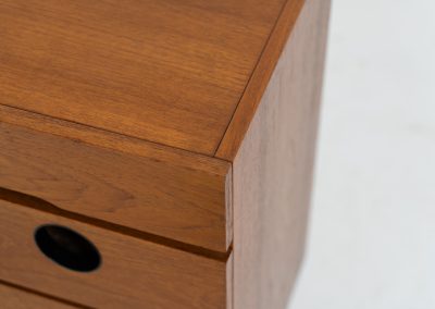Teak shoe cabinet (Germany, 1960s). The cabinet features two small drawers and three shelves for shoe storage. It is made of teak and has a black lacquered frame with black inset handles that allow for proper ventilation. The cabinet is in good condition, with some visible signs of use.