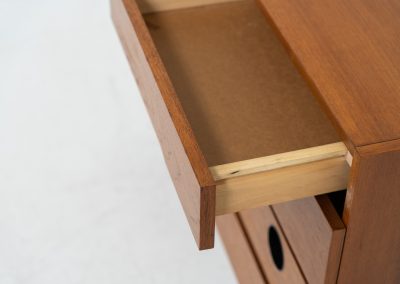Teak shoe cabinet (Germany, 1960s). The cabinet features two small drawers and three shelves for shoe storage. It is made of teak and has a black lacquered frame with black inset handles that allow for proper ventilation. The cabinet is in good condition, with some visible signs of use.
