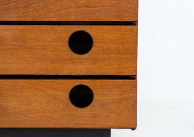 Teak shoe cabinet (Germany, 1960s). The cabinet features two small drawers and three shelves for shoe storage. It is made of teak and has a black lacquered frame with black inset handles that allow for proper ventilation. The cabinet is in good condition, with some visible signs of use.
