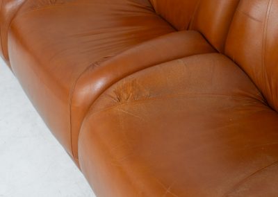 Modular sofa by Doimo Salotti (Italy, 1970s). Striking and bold modular seating system consisting of five identical elements and one corner piece, upholstered in their original cognac leather. Can be arranged as a sofa or used as individual lounge chairs. Low, sculptural design with generous padding, offering both strong visual impact and excellent comfort. The sofa is in very good condition with some age-related signs of use, as shown in the pictures. Most traces of use are discreet and not immediately visible. Marked by the maker.