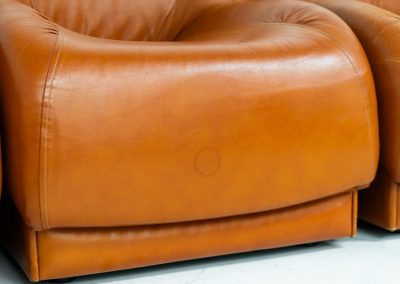 Modular sofa by Doimo Salotti (Italy, 1970s). Striking and bold modular seating system consisting of five identical elements and one corner piece, upholstered in their original cognac leather. Can be arranged as a sofa or used as individual lounge chairs. Low, sculptural design with generous padding, offering both strong visual impact and excellent comfort. The sofa is in very good condition with some age-related signs of use, as shown in the pictures. Most traces of use are discreet and not immediately visible. Marked by the maker.