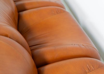 Modular sofa by Doimo Salotti (Italy, 1970s). Striking and bold modular seating system consisting of five identical elements and one corner piece, upholstered in their original cognac leather. Can be arranged as a sofa or used as individual lounge chairs. Low, sculptural design with generous padding, offering both strong visual impact and excellent comfort. The sofa is in very good condition with some age-related signs of use, as shown in the pictures. Most traces of use are discreet and not immediately visible. Marked by the maker.