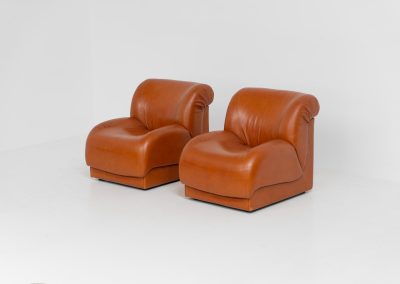 Modular sofa by Doimo Salotti (Italy, 1970s). Striking and bold modular seating system consisting of five identical elements and one corner piece, upholstered in their original cognac leather. Can be arranged as a sofa or used as individual lounge chairs. Low, sculptural design with generous padding, offering both strong visual impact and excellent comfort. The sofa is in very good condition with some age-related signs of use, as shown in the pictures. Most traces of use are discreet and not immediately visible. Marked by the maker.